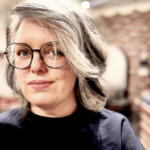 Woman with glasses and short gray hair.